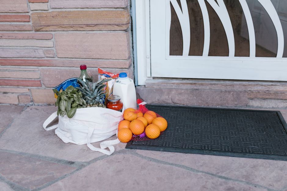A cloth shopping bag of fresh groceries including greens and oranges