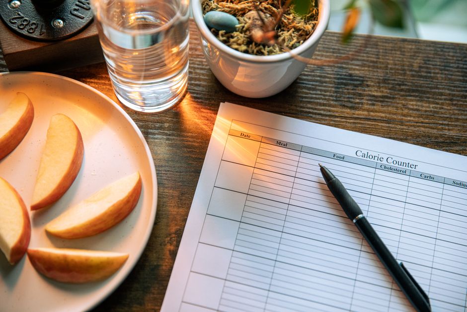 Glass of water and apple slices beside a calorie-counter table