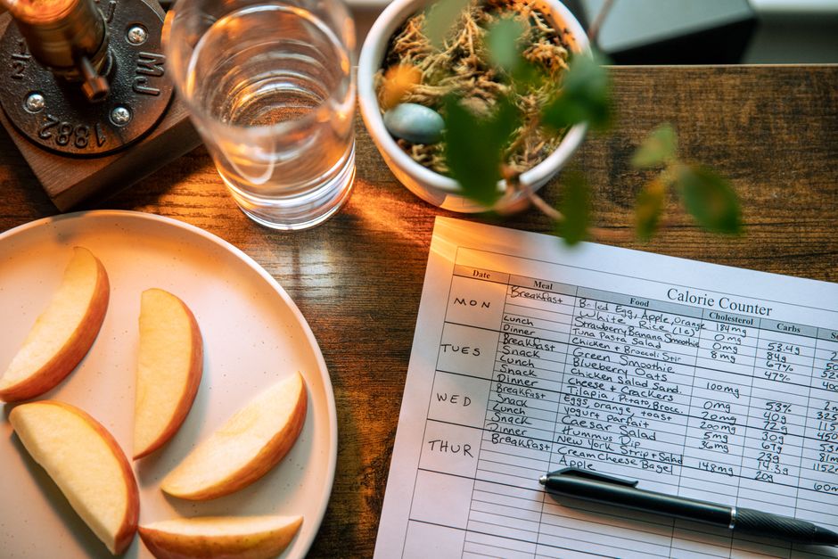 Food logging with a glass of water and apple slices on a wooden table