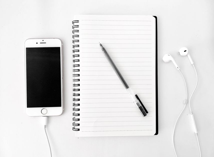 A food diary notebook and pen beside a smartphone