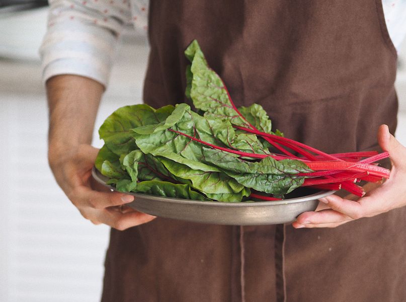 Fresh chard being carried on a metal dish in a kitchen